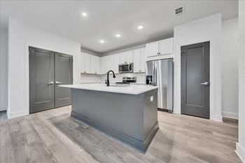 A modern kitchen with a grey island and stainless steel appliances.